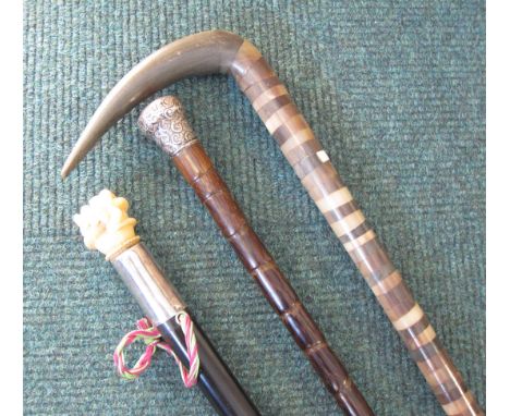 An ebony Walking Cane with carved ivory hand and serpent handle and white metal collar, a Victorian bamboo Walking Cane with 