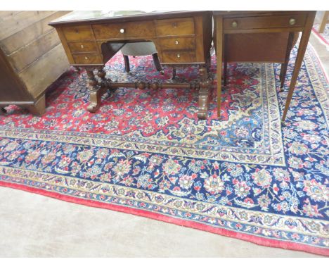 A red ground woollen Carpet with blue floral central motif and blue borders, 14ft 2in x 9ft