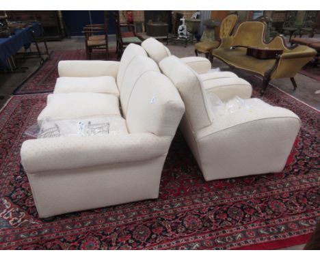 A cream upholstered three seater Sofa with shaped hump back on bun feet, with a matching pair of more recent Armchairs