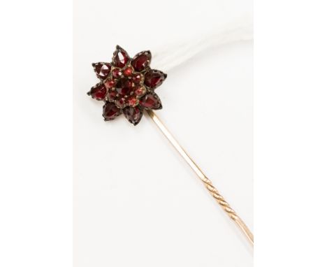 A Victorian garnet and rose metal flower head stick pin, the centre round mixed cut garnet with round mixed cut garnet surrou