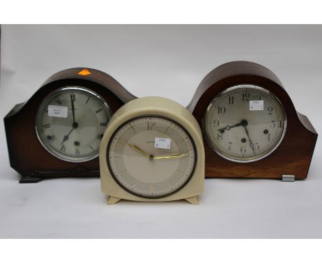 A cream coloured Smiths Bakelite mantle clock, with two veneered mantle clocks 