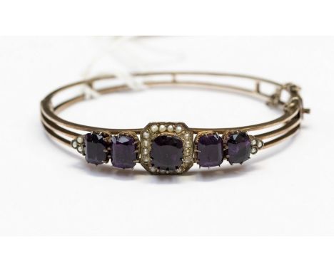 A Victorian amethyst and seed pearl rose  metal bangle comprising centre claw set raised amethyst with seed pearl surround, w