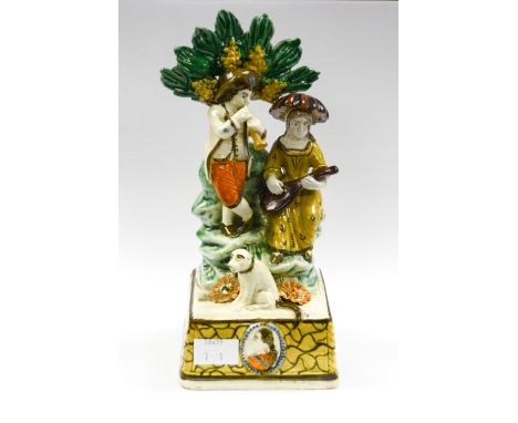 A Prattware type Bocage figure of two Musicians and a Dog on a rocky mound. The high base in yellow with black lines with a p
