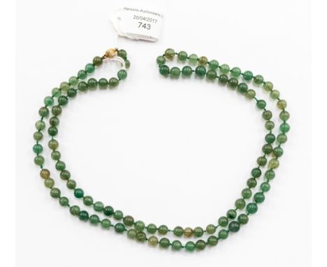 A jade bead necklace, of roughly inform spherical beads, yellow metal clasp, stamped .375