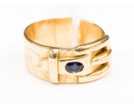 A 9ct gold gents buckle ring set with two sapphires either side of the buckle, measuring approx 10mm wide,  size U,  with a t