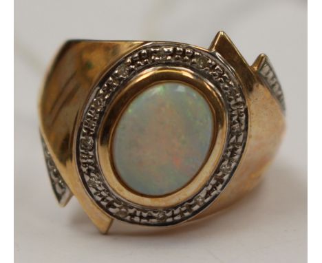 A 9ct gold ring set with an oval opal surround by small diamond chips in white gold, size T, with a total gross weight approx