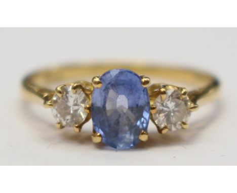 A Ceylon sapphire and diamond three stone 18ct yellow gold ring, the two round brilliant diamonds with a total diamond weight