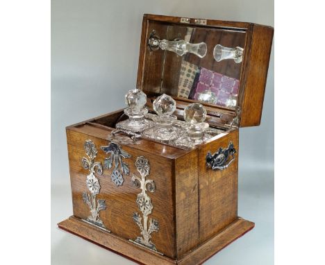 Late Victorian oak three section tantalus and games compendium comprising three cut glass square section decanters and stoppe
