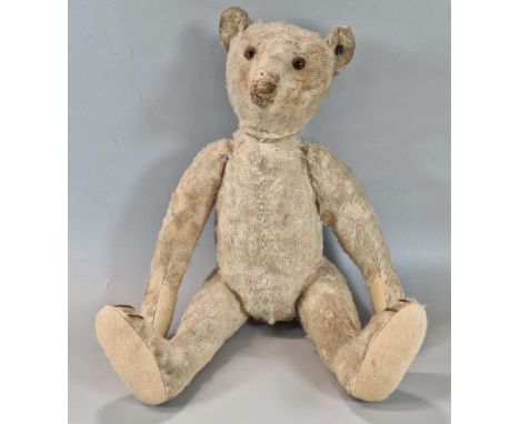 Early 20th century Steiff plush teddy bear, straw filled, with silver button to left ear, having glass eyes, long arms, hump 