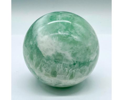 A beautiful spherical stone carved figure in natural shades of light green. Fluorite is believed to restore peace of mind and