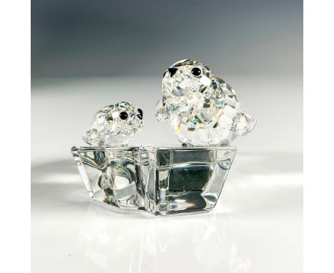 A clear crystal figurine of a seal and its child laying on a land mass. Black crystals are used to decorate the eyes and snou
