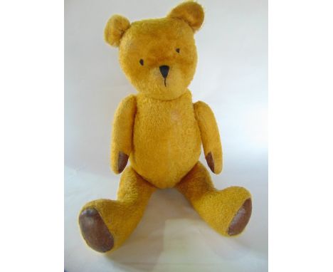 A large antique straw filled teddy bear with jointed limbs, sewn woollen eyes and nose, 83cm (when standing) 