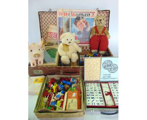 A vintage stitched suitcase containing various toys to include an antique teddy bear in red dungarees, a Gund teddy bear, a h