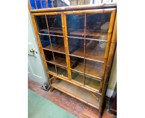 A late 19th century bamboo framed bookcase enclosed by two half length doors with open shelf work below and above, fitted wit