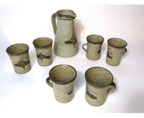 A Leach Pottery six place lemonade set comprising a jug and six mugs, all with painted stylised leaf decoration in brown and 