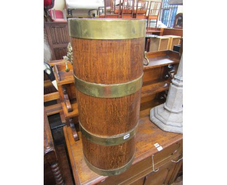 An Edwardian oak stick stand of cylindrical tapering form with brass banded detail with lion mask and ring handles