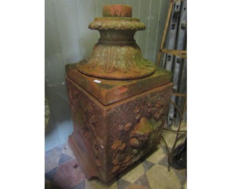 A terracotta garden urn pedestal/plinth with raised facemask, trailing ivy and further foliate detail and step moulded square