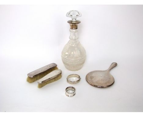 A heavy cut glass decanter with silver collar and mushroom shaped stopper, three pieces of silver backed dressing table ware,