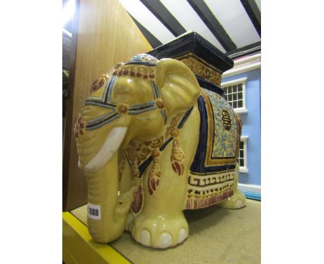 A contemporary ceramic garden seat in the form of an elephant with brightly coloured head dress and saddle