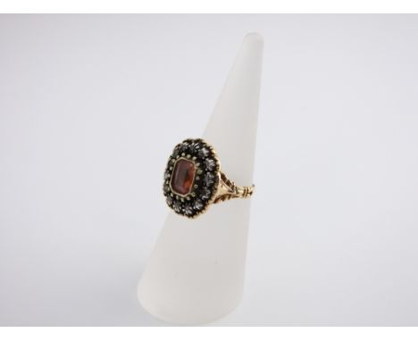 A 14ct gold pink stone and diamond set ring, the central stone surrounded by fourteen diamonds, size K