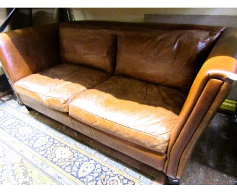 A good quality contemporary leather Laura Ashley sofa of club shape in a mid tan coloured finish, raised on square tapered su