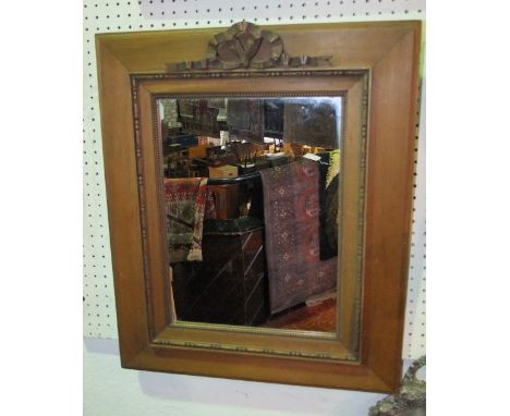 A timber framed portrait wall mirror set within a stepped frame with beaded and carved border beneath an applied carved garla
