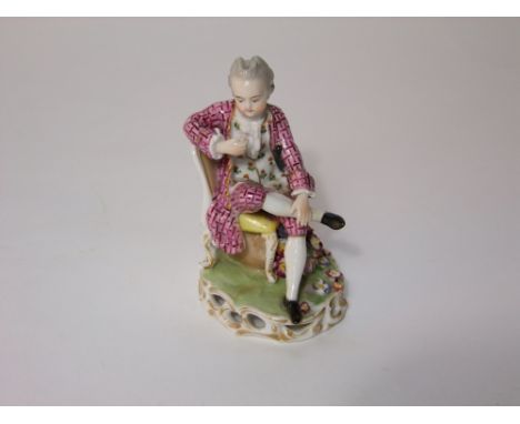 A 19th century ceramic figure of a seated gentleman in 18th century style costume, in the Chelsea manner, raised on a pierced