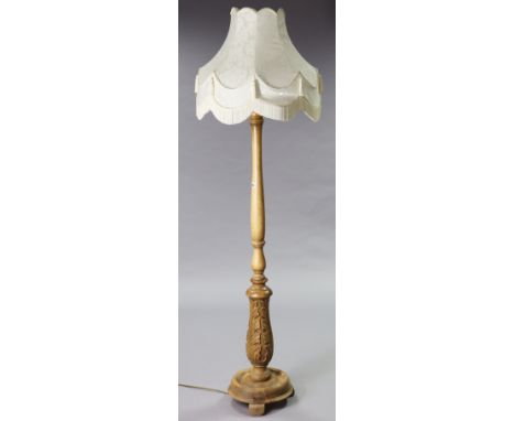 A beech standard lamp with a turned &amp; carved vase-turned centre column &amp; circular base, with shade.