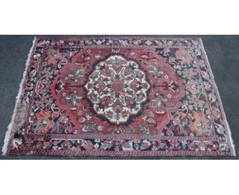 A Bakhtiar carpet of madder ground with&nbsp;central medallion &amp; all-over repeating geometric designs in blue stylised bo