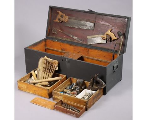 A black painted deal tool-chest enclosed by a hinged lift-lid, &amp; with wrought-iron side handles, 91cm wide x 34cm high x 