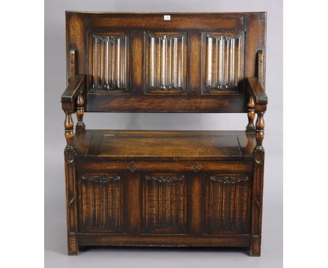 A reproduction oak monk’s bench with fold-over top, hinged box-seat, &amp; carved linen-fold panels to the front &amp; sides,