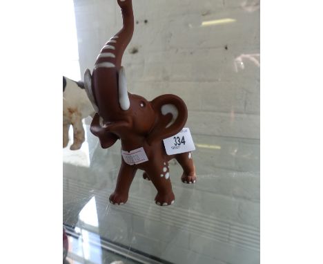 A Goebel model of an elephant, trunk raised.