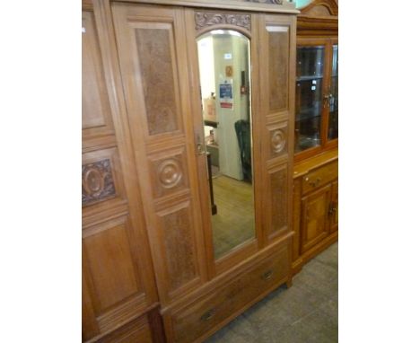 An Edwardian satin walnut wardrobe, the central door with carved frieze, bevel glass mirror, flanked by two panelled sections