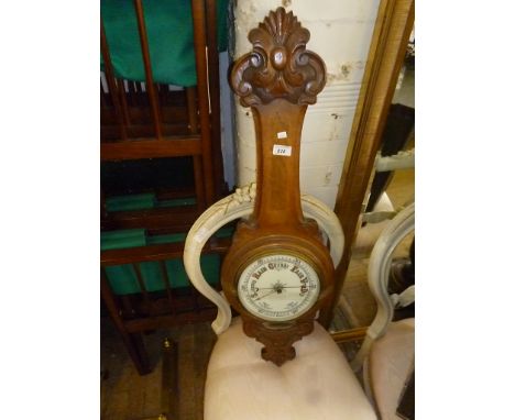 A late 19th/early 20th Century oak framed aneroid barometer, the white dial with Arabic numerals, the frame with carved decor