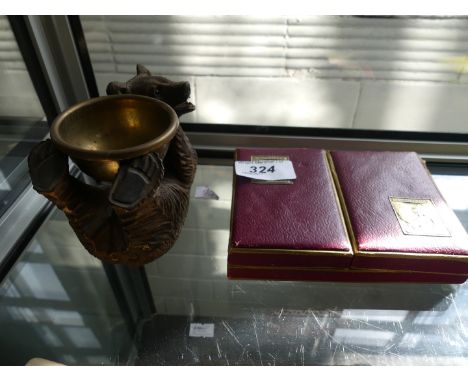 A Black Forest bear holding a small brass bowl and two cased sets of Boddingtons playing cards.