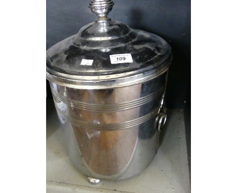 A chromed cylindrical coal bucket with cover and ring handles.