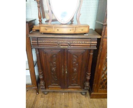 A continental carved oak small sideboard early 20th CenturyWith frieze drawer with elaborate brass drop handle, with two cent