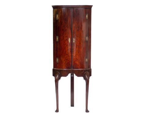 A mid 18th Century mahogany bow-fronted corner cupboard:, on a later stand, the upper part with a moulded cornice and fixed s