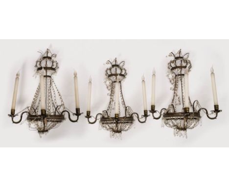 A set of three late 19th century brass and glass lustre three -branch wall lights: of bow-fronted outline, with scrolling bra