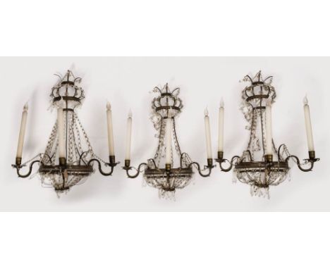 A set of three late 19th century brass and glass lustre three -branch wall lights: of bow-fronted outline, with scrolling bra