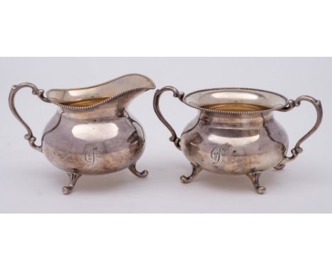A Sterling silver sugar basin and matching cream jug, stamped marks: of circular outline with beaded rims, scroll handles and