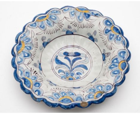 A Brislington polychrome delftware lobed dish: painted in blue, manganese and yellow with a central floral spray within conce