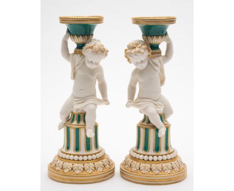 A pair of Minton coloured parian 'Putti' candlesticks: decorated in green enamels and gilt, on fluted columns with bead and a