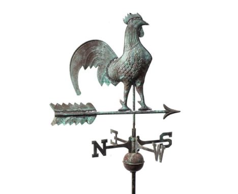 An embossed copper weather vane: in the form of a cockerel perched on an arrow, mounted on a ball spire with the four cardina