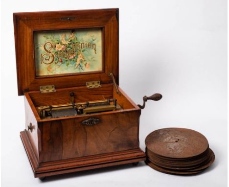 A late 19th/early 20th century walnut cased symphonium: the quarter veneered top with print of a musical putto to underside, 