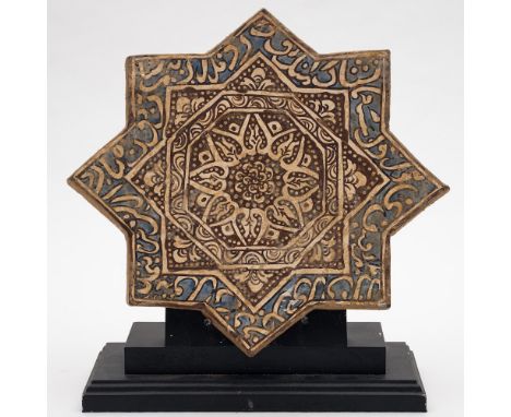 A Persian star shaped pottery tile: of Kashan type the centre painted in brown and white with a flower motif, narrow border a