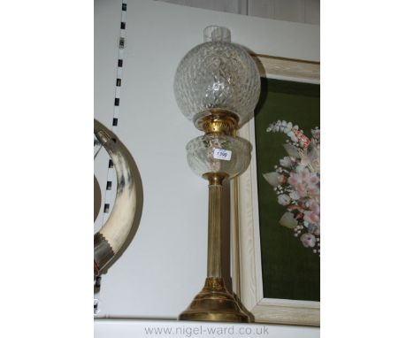 A Brass Oil Lamp with clear glass reservoir and glass globe shade.