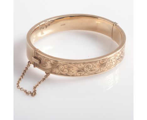 9ct gold ladies hinged bangle, with engraved decoration to one side, and safety chain fastening. Gross weight 17 grams  
