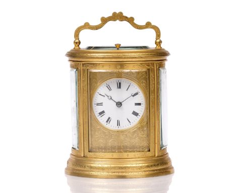 A 19TH CENTURY FRENCH OVAL GILT BRASS CARRIAGE CLOCK the white enamel Roman dial with scroll engraved mask, Petite Sonnerie m