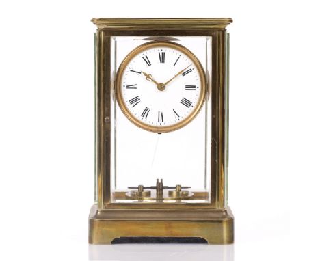 A BRASS FOUR GLASS TORSION TIMEPIECE with white enamel Roman dial, doors front and rear with thick bevelled glass sides, 27cm